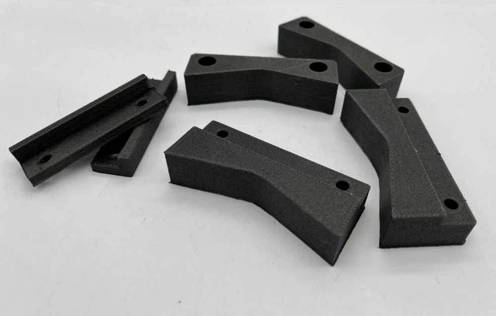 Mehrere schwarze, additiv gefertigte technische Bauteile